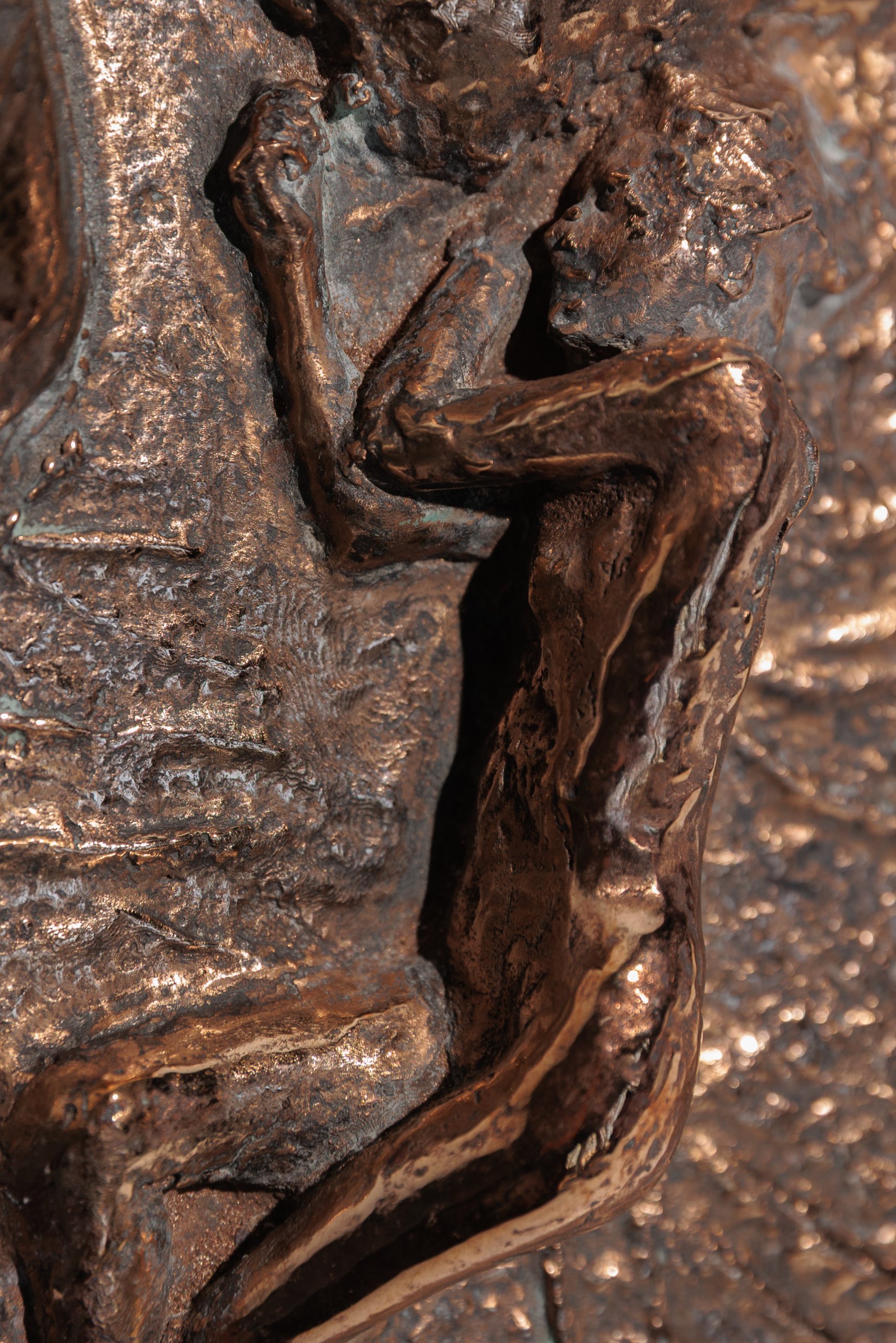 Close-up of the bronze figure's arm, head, and torso